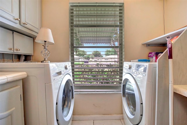 washroom featuring cabinet space, tile patterned flooring, and washing machine and clothes dryer