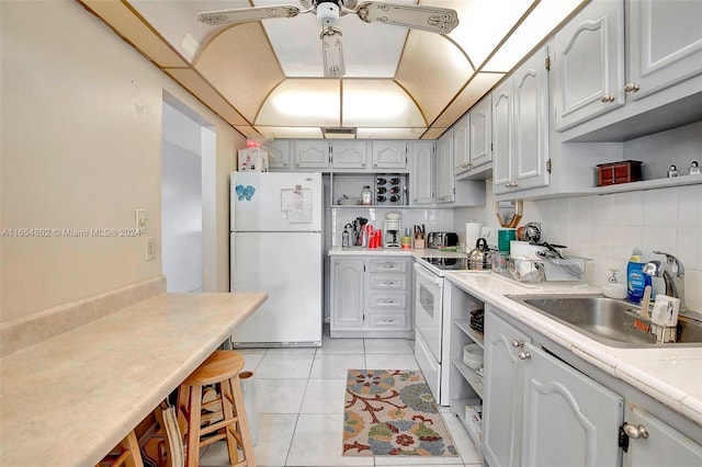 kitchen featuring open shelves, white appliances, light tile patterned floors, and a sink