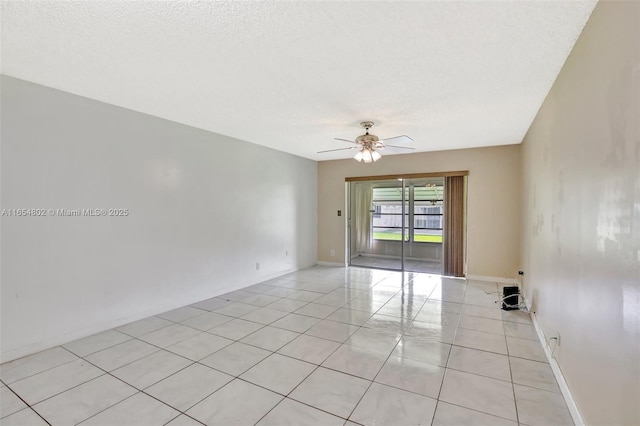 empty room with ceiling fan, light tile patterned floors, and a textured ceiling
