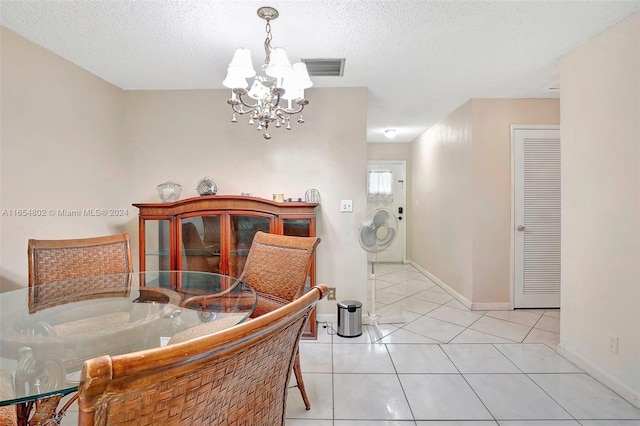 dining area featuring light tile patterned floors, visible vents, a textured ceiling, and a notable chandelier