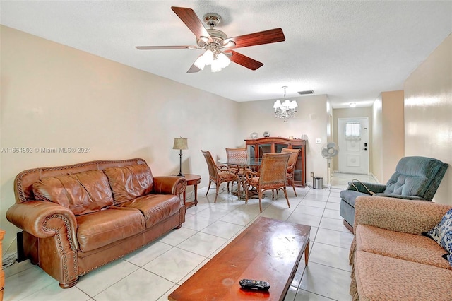 living room with visible vents, baseboards, light tile patterned floors, ceiling fan with notable chandelier, and a textured ceiling