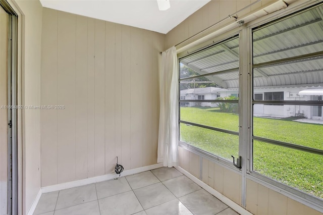 interior space with baseboards, light tile patterned floors, plenty of natural light, and wooden walls