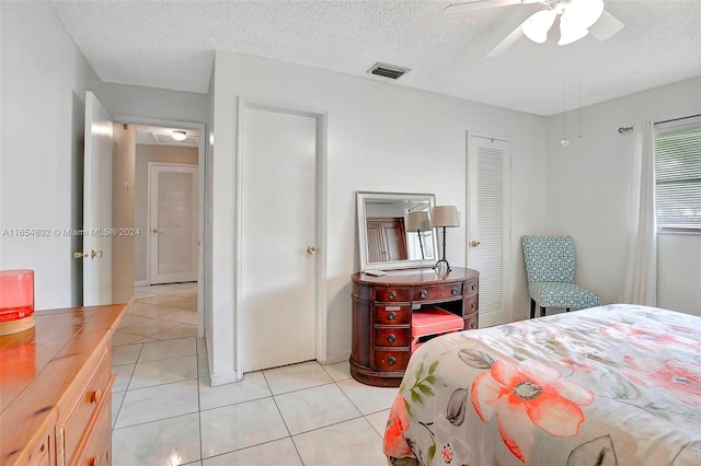 bedroom with light tile patterned floors, visible vents, a textured ceiling, and a ceiling fan