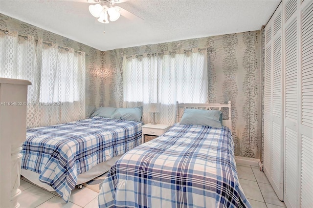 tiled bedroom featuring a closet, multiple windows, a textured ceiling, and wallpapered walls