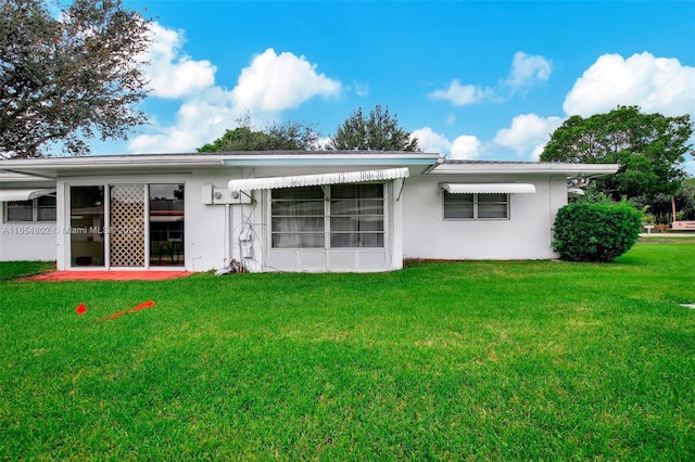 rear view of house with a lawn and stucco siding