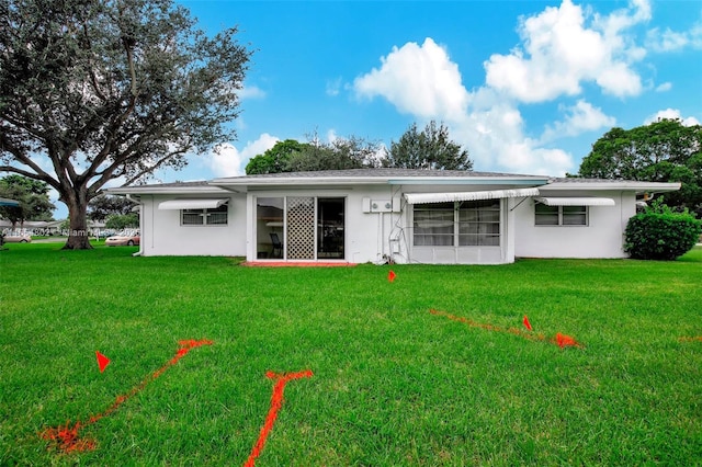 rear view of property with a lawn and stucco siding