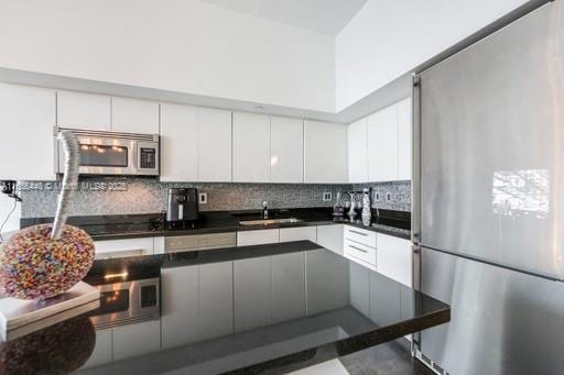 kitchen featuring stainless steel appliances, white cabinets, tasteful backsplash, and sink