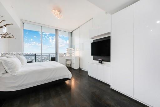 bedroom featuring a wall of windows and dark hardwood / wood-style floors