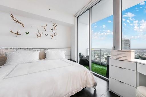 tiled bedroom with a wall of windows and multiple windows