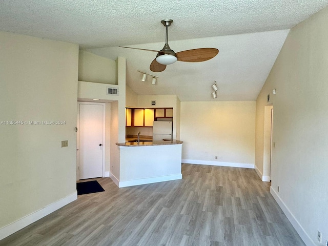 kitchen with high vaulted ceiling, a textured ceiling, ceiling fan, white fridge, and hardwood / wood-style flooring