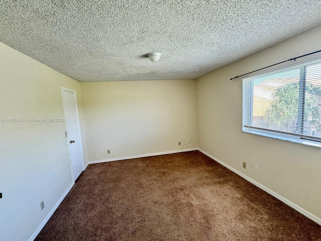 unfurnished room with dark colored carpet and a textured ceiling