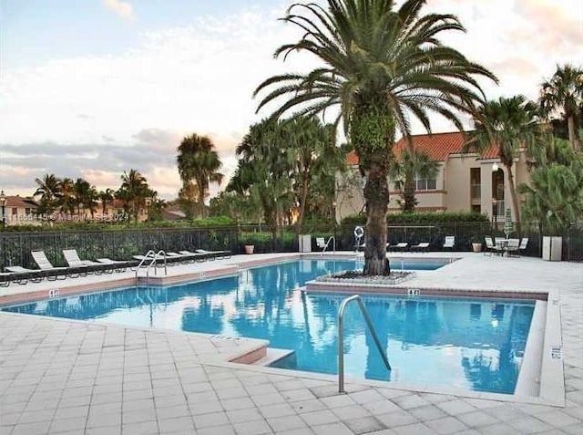 pool at dusk featuring a patio