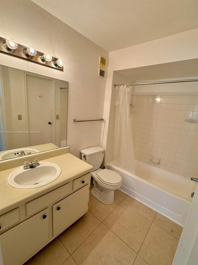 full bathroom featuring a textured ceiling, toilet, shower / bath combo with shower curtain, vanity, and tile patterned flooring