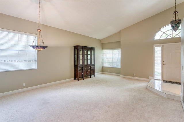 foyer with high vaulted ceiling, a healthy amount of sunlight, and carpet floors