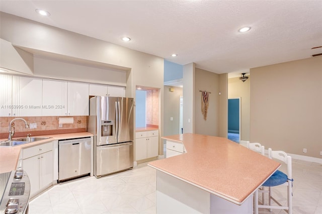 kitchen featuring white cabinets, appliances with stainless steel finishes, sink, and a center island