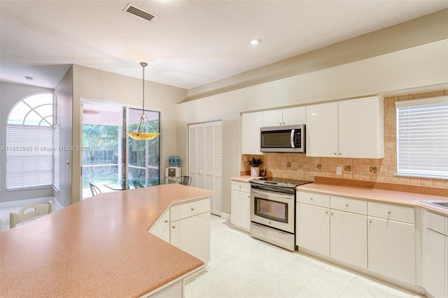 kitchen with white cabinetry, appliances with stainless steel finishes, tasteful backsplash, a textured ceiling, and hanging light fixtures