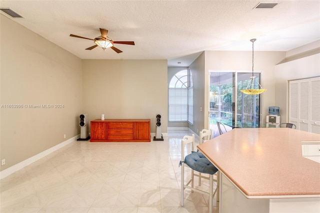 kitchen with a textured ceiling, ceiling fan, and decorative light fixtures