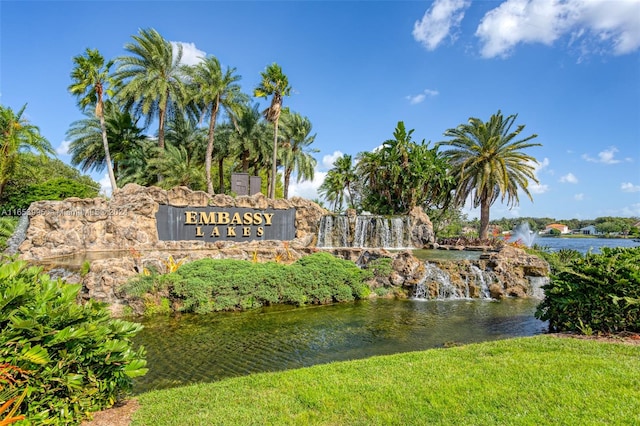 community / neighborhood sign with a water view and a lawn