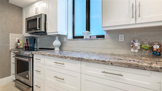 kitchen featuring appliances with stainless steel finishes, light stone counters, and white cabinetry