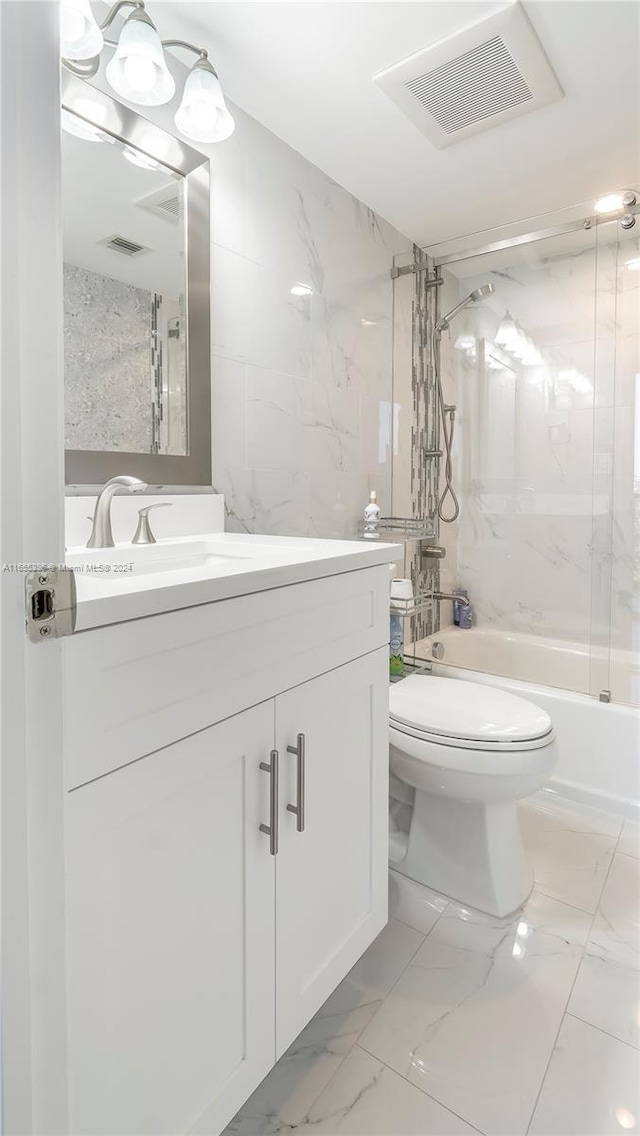 full bathroom with tile walls, toilet, tiled shower / bath combo, and vanity