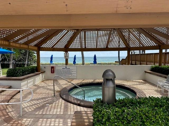 exterior space with a community hot tub, a water view, and a gazebo