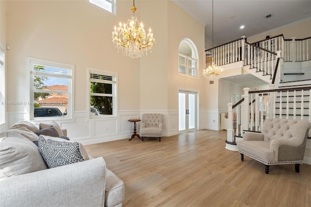 living room with a high ceiling, an inviting chandelier, ornamental molding, and wood-type flooring