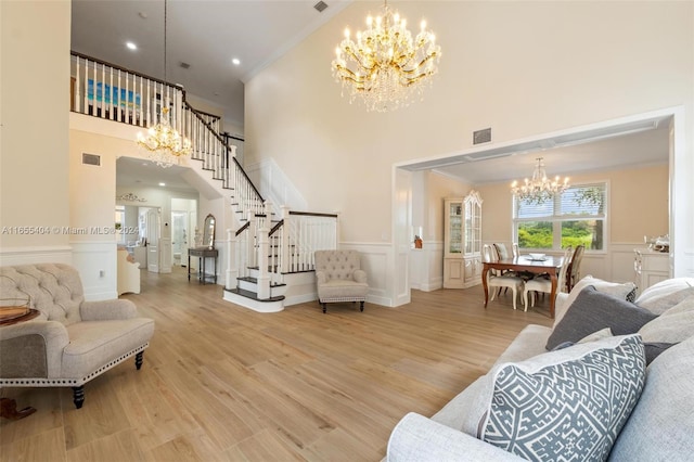 living room featuring crown molding, an inviting chandelier, a towering ceiling, and hardwood / wood-style flooring