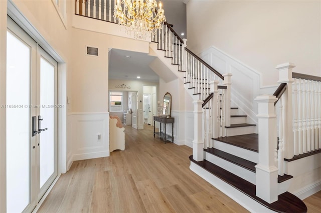 stairway featuring a chandelier, french doors, a towering ceiling, and hardwood / wood-style flooring