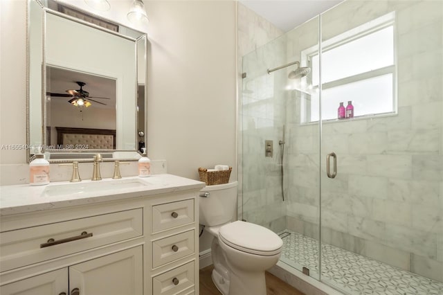 bathroom featuring ceiling fan, wood-type flooring, toilet, vanity, and a shower with shower door