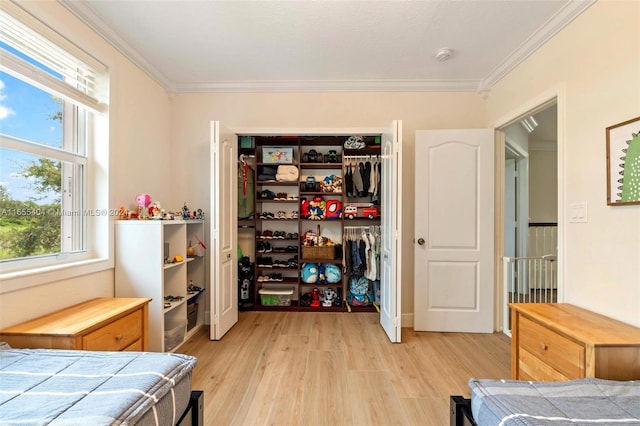 bedroom with light wood-type flooring, a closet, and crown molding