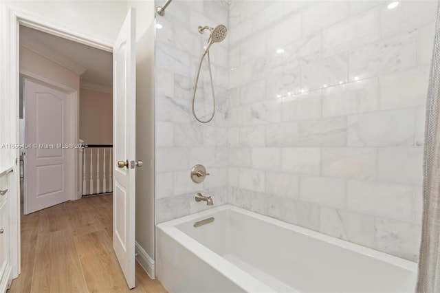 bathroom with tiled shower / bath combo, hardwood / wood-style flooring, and ornamental molding