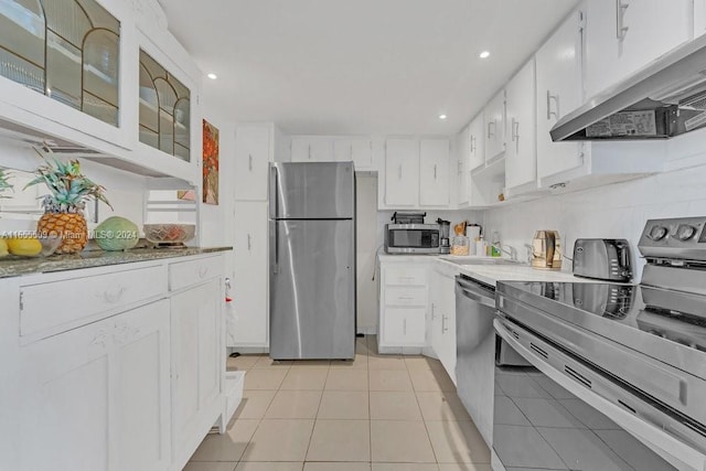 kitchen featuring appliances with stainless steel finishes, sink, light tile patterned floors, and white cabinets