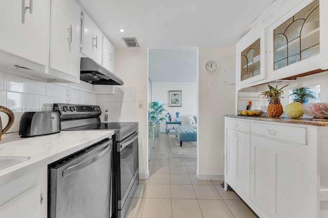 kitchen featuring white cabinets, light tile patterned floors, appliances with stainless steel finishes, light stone countertops, and tasteful backsplash