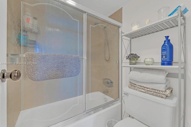 bathroom with toilet and bath / shower combo with glass door