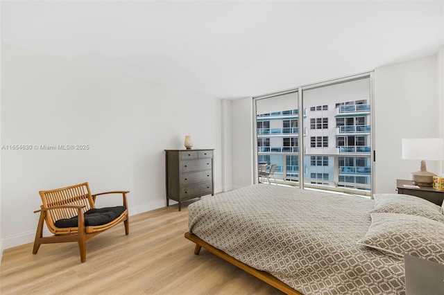 bedroom featuring baseboards, a wall of windows, and wood finished floors