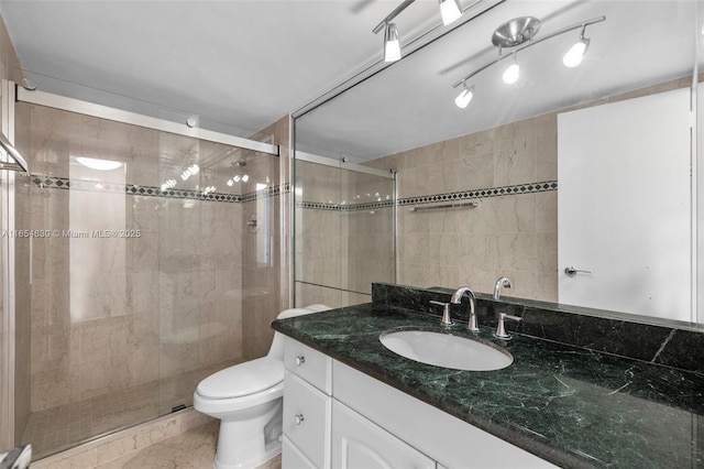 bathroom with toilet, vanity, a shower stall, and tile walls