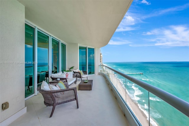 balcony featuring a view of the beach, a water view, and outdoor lounge area