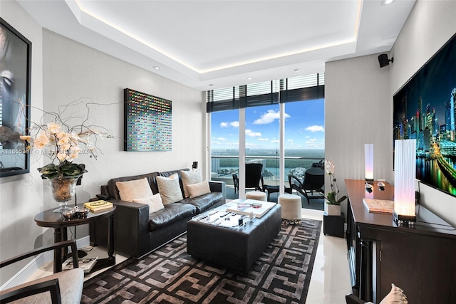 living room with a raised ceiling and floor to ceiling windows