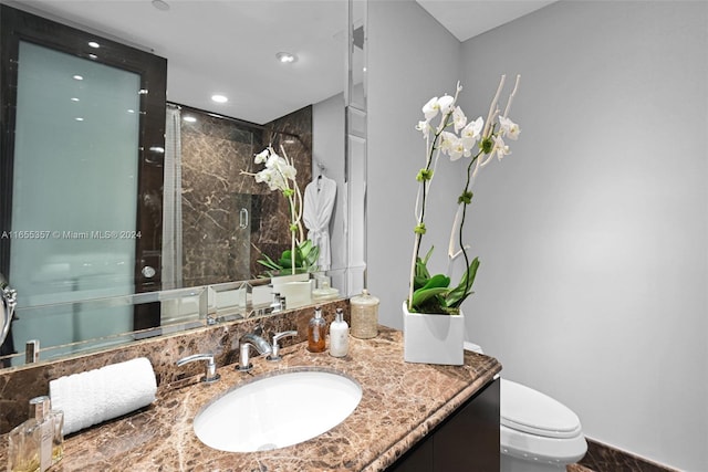 bathroom featuring a shower with door, toilet, and vanity