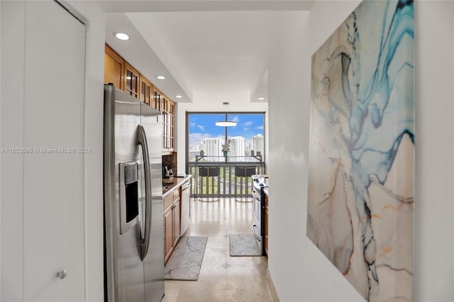 kitchen featuring floor to ceiling windows, stainless steel appliances, and decorative light fixtures