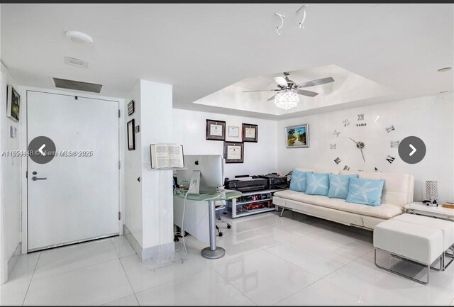 office area with ceiling fan, light tile patterned flooring, and a tray ceiling