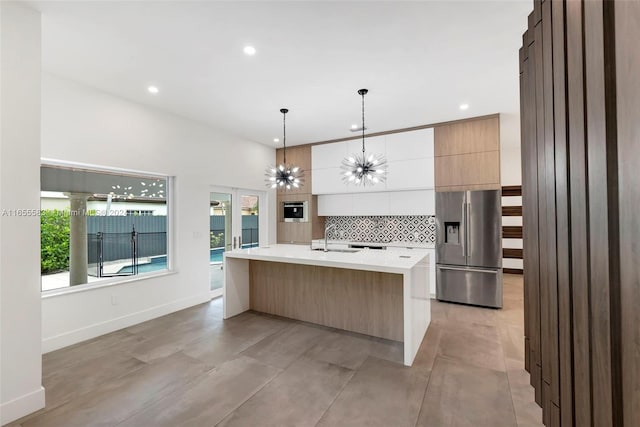 kitchen with white cabinetry, sink, a center island with sink, decorative backsplash, and stainless steel fridge with ice dispenser