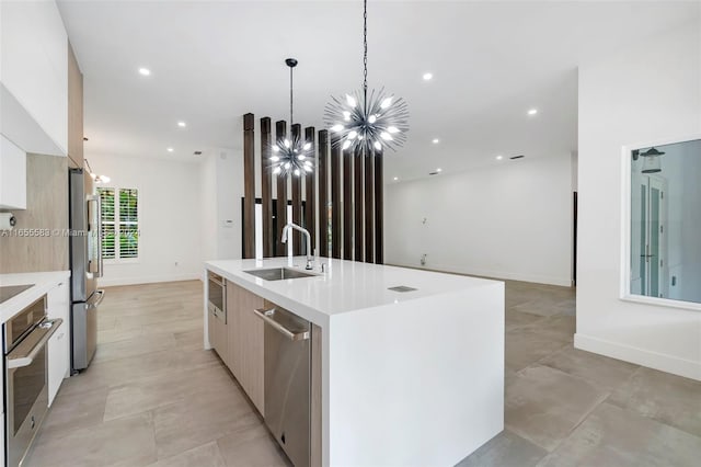 kitchen featuring a notable chandelier, an island with sink, sink, hanging light fixtures, and appliances with stainless steel finishes