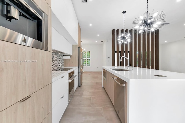 kitchen featuring appliances with stainless steel finishes, sink, an island with sink, pendant lighting, and decorative backsplash