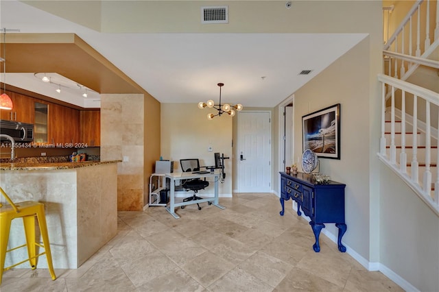 kitchen with pendant lighting, a chandelier, light stone counters, and tile walls