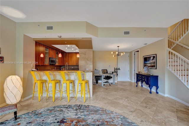 kitchen featuring kitchen peninsula, a breakfast bar area, a chandelier, and sink