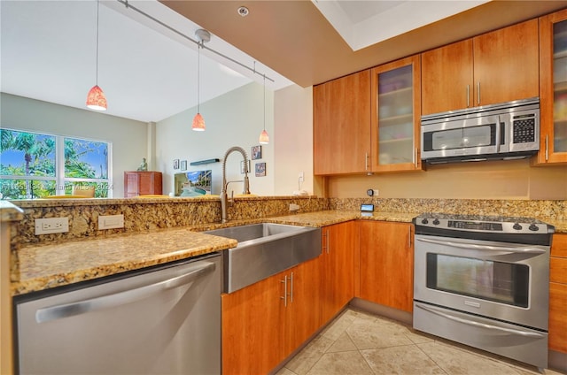 kitchen featuring decorative light fixtures, sink, light stone counters, stainless steel appliances, and kitchen peninsula