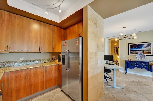 kitchen with light stone countertops, a chandelier, stainless steel fridge, and light tile patterned floors