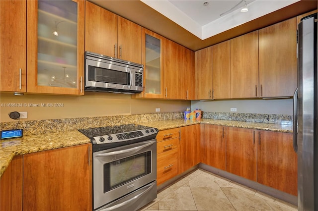 kitchen with appliances with stainless steel finishes, light stone counters, and light tile patterned floors