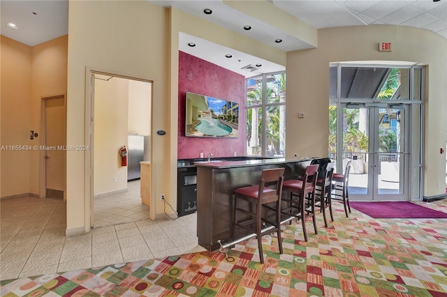 kitchen featuring french doors, a breakfast bar area, light tile patterned floors, and kitchen peninsula